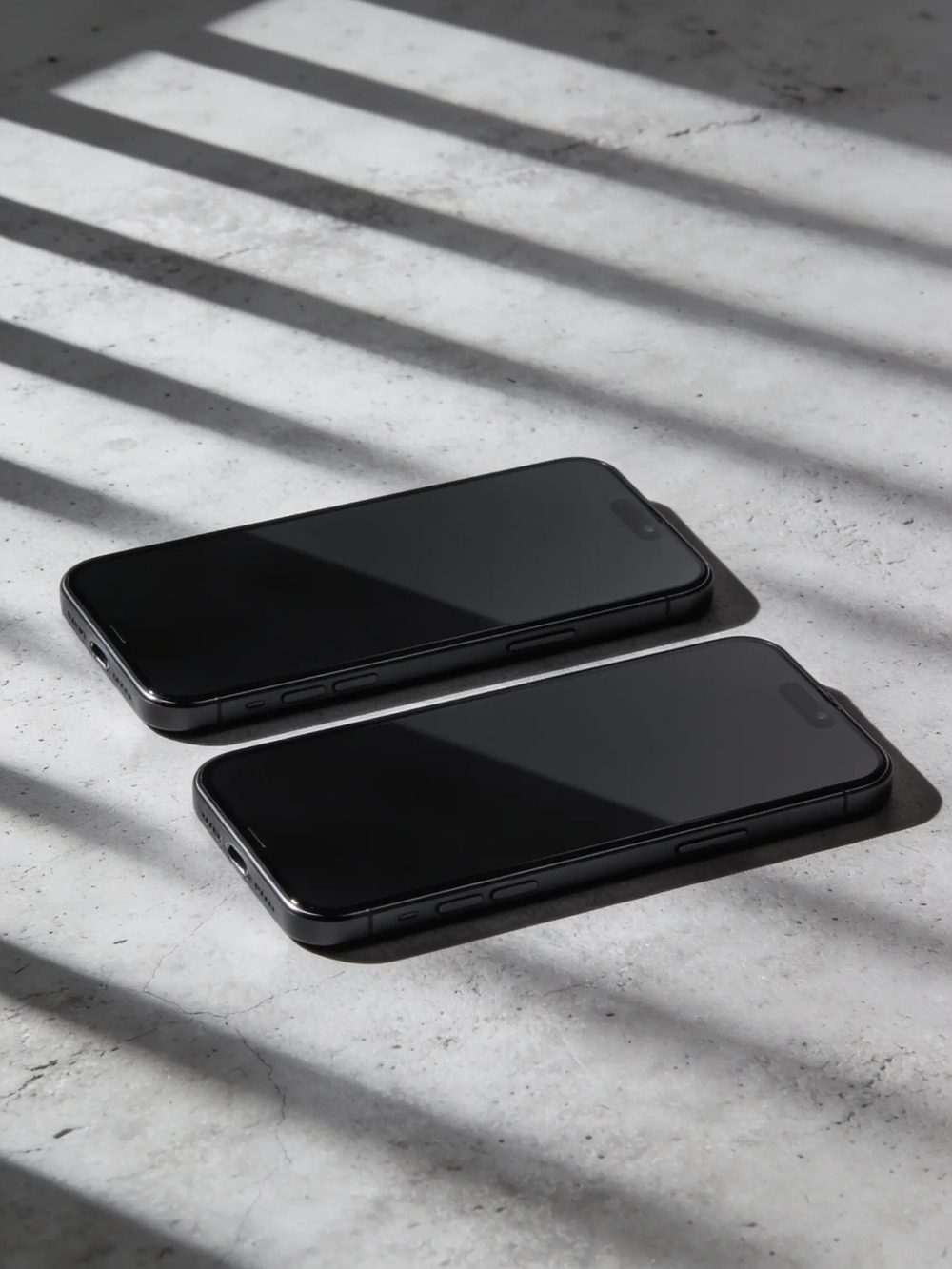 Two identical smartphones side by side on a grey concrete surface